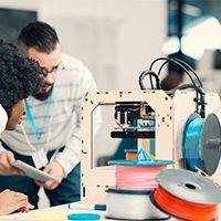 servo motor for 3D printer Diversity startup business team working together by 3D printer. Looking at printer working and discussing. Man with beard and headphones around his neck holding digital tablet out and explaining to his african female coworker. Other coworkers working smoothly in background